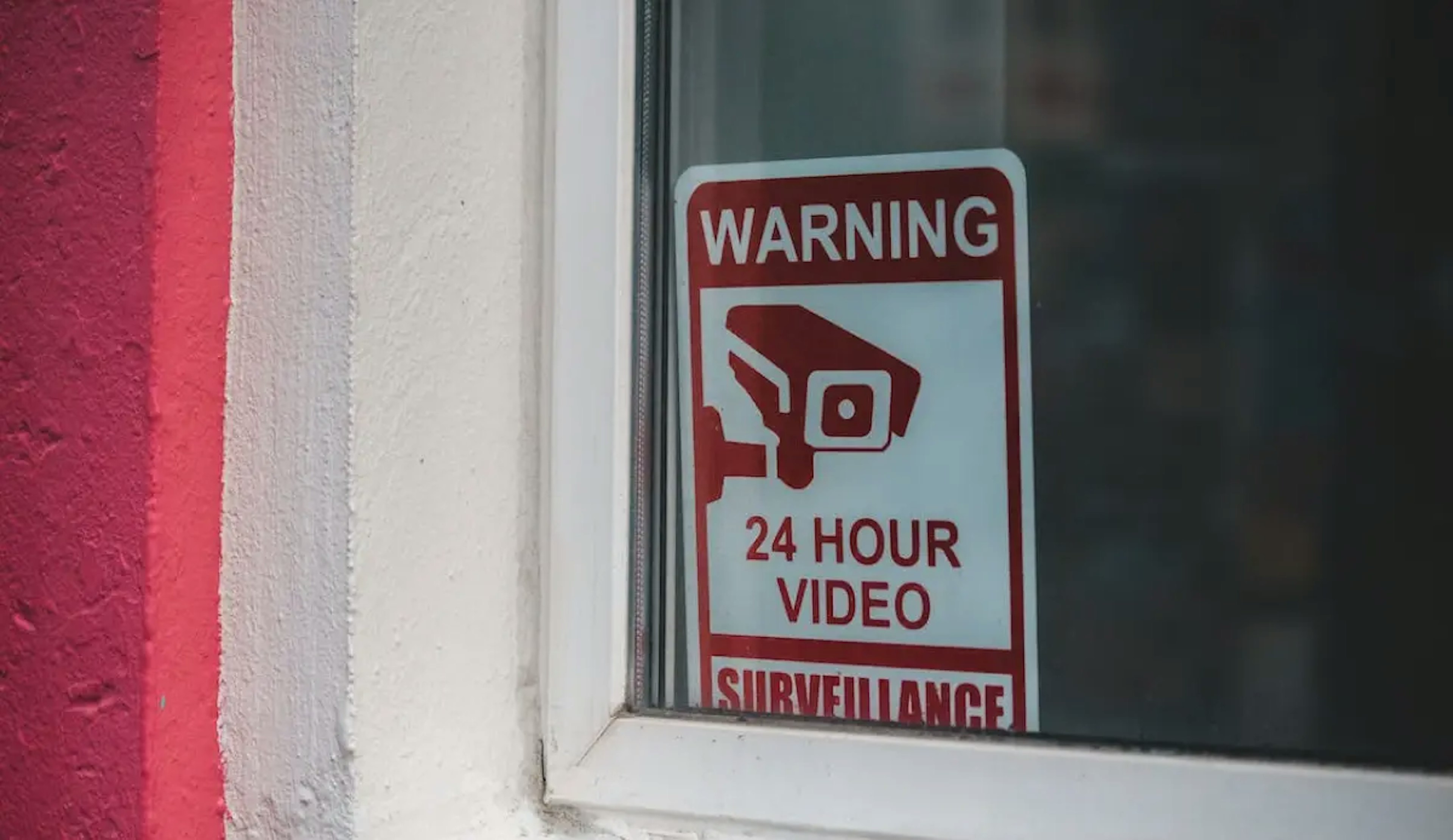 A sign with a security camera symbol and text that reads "WARNING 24 hour video surveillance"
